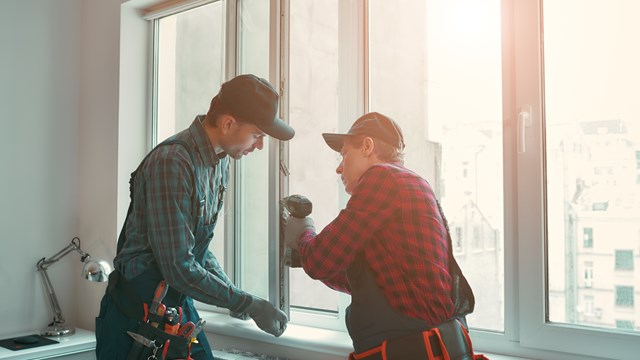 Portrait of mature men wearing uniform standing indoors and installing new windows in the apartment. Horizontal shot