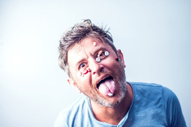 Funny man with a lot of different pills on his face. Medicine concept