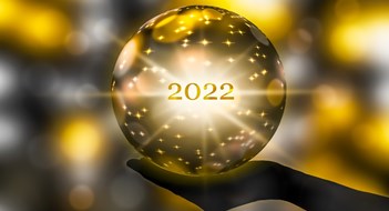 The Year in (P)Review golden crystal ball in a hand, prediction for 2022, brights stars and sparks on abstract shiny background