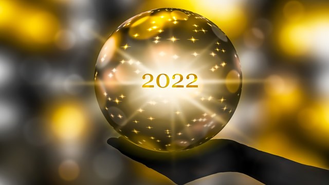 golden crystal ball in a hand, prediction for 2022, brights stars and sparks on abstract shiny background