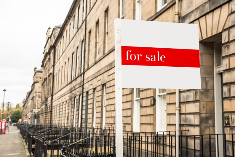 For sale sign in front of an old stone terraced house in a city centre on a cloudy autumn day. Edinburgh, Scotland, UK.