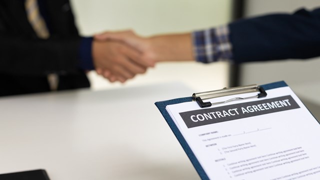 Handshake and contract signing an agreement.