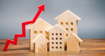 Gov't Regulations Account for 40.6% of Multifamily Development Costs Miniature wooden houses and red arrow up. The concept of increasing the cost of housing. High demand for real estate. The growth of rent and mortgage rates. Sale of apartments. Population grows