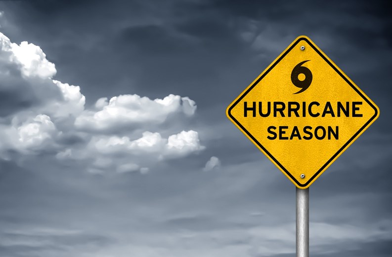 Yellow caution sign with black hurricane symbol, stormy sky in background 