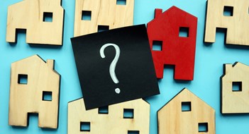Insurance in the Multifamily Setting Tiny wooden houses and question mark. Home valuation and selection.