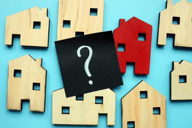 Tiny wooden houses and question mark. Home valuation and selection.