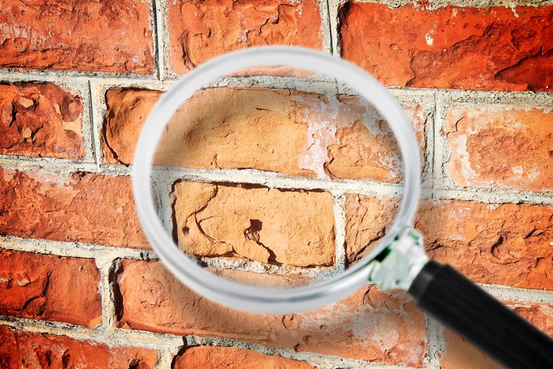 Old italian brick wall with damaged bricks - Concept image seen through a magnifying glass.