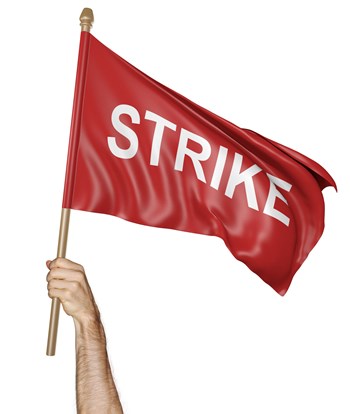 A man raising a red flag high in the air with the word strike on it.