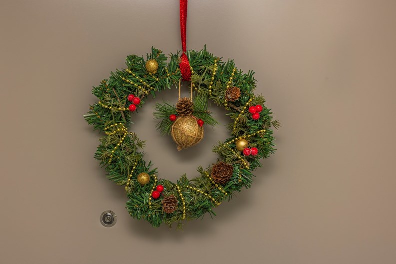 Close up view of Christmas wreath of spruce branches hanging on apartment front door.