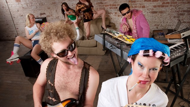 Young guitarist teasing woman in curlers at a 1970s Disco Music Party