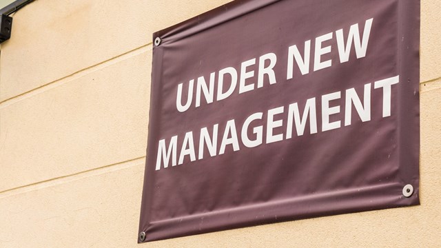 under new management sign banner on wall ouside shop in england.