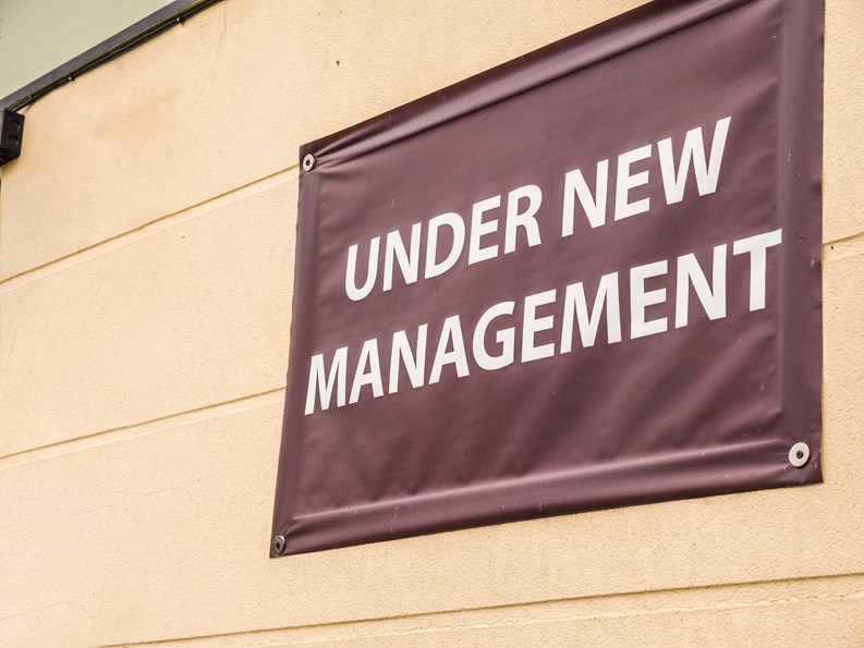 under new management sign banner on wall ouside shop in england.