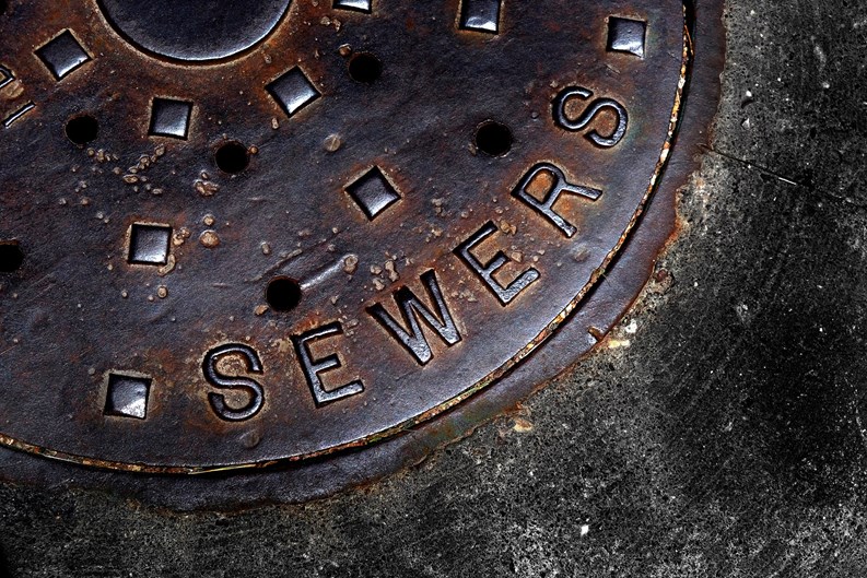 Man hole cover for sewer entry with iron grate on street in a city