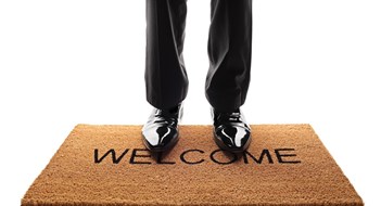 Board Resource Guide: Training the Board Pair of legs standing on a doormat with the word welcome written on it isolated on white background