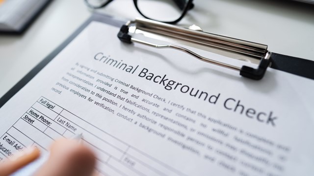Close-up Of Human Hand Filling Criminal Background Check Application Form With Pen