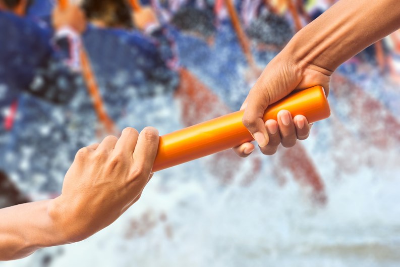 hands passing a relay baton on rowing team background and color tone effect.