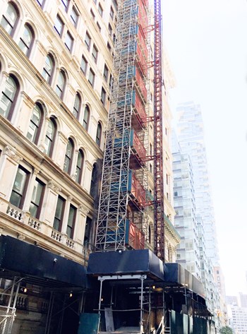 Looking up at the beautiful windows of a New York City Building. Construction scaffolding / elevator