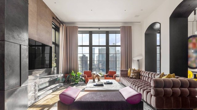 Modern urban living area with couches, fireplace, and large windows overlooking the city