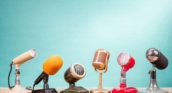 Q&A: Recording Board Meetings Retro old microphones for press conference or interview on table front gradient aquamarine background. Vintage old style filtered photo