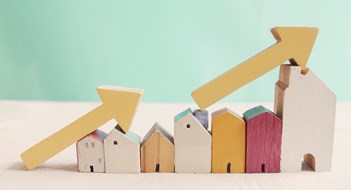 Insurance Premiums Skyrocket Wooden houses with yellow arrows up. housing boom, property market growing, high demand for real estate, house prices rising concept