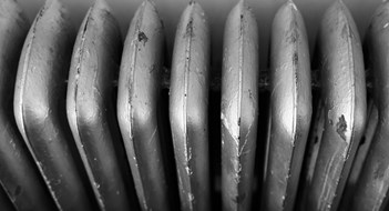 Converting to Electricity-Based HVAC An old dark brown radiator in a kitchen