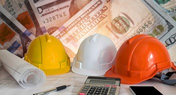New Law Affects Contractor Retainage for Co-ops & Condos Architectural blueprint with safety helmet and tools on blur dollar money background.