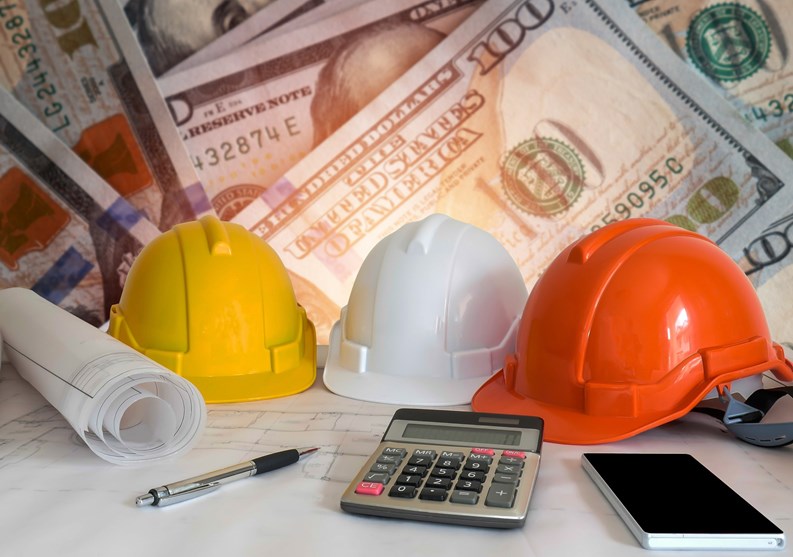 Architectural blueprint with safety helmet and tools on blur dollar money background.