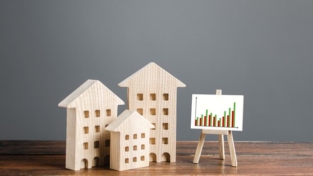 Residential buildings and easel with a positive growth trend chart. Market growth, attracting investment. Raising taxes and house maintenance. Real estate price increases. High demand and value