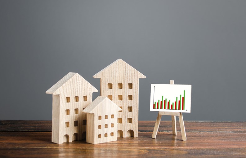 Residential buildings and easel with a positive growth trend chart. Market growth, attracting investment. Raising taxes and house maintenance. Real estate price increases. High demand and value