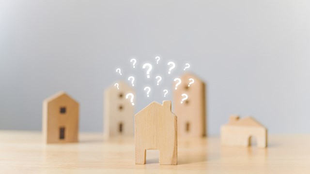 Real estate developer and managing property investment concept. Selective focus wooden houses with question mark on wood table