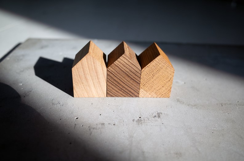 Group of similar wooden tiny toy houses. Wooden models of buildings as conceptual images for real estate topics.