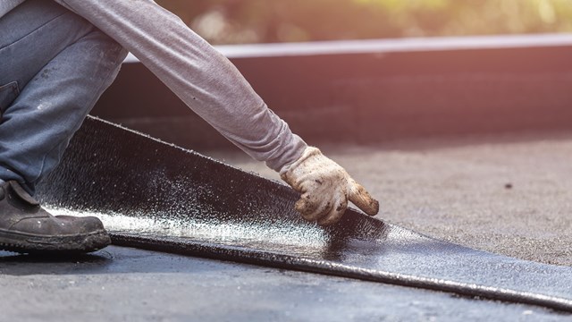 Asia worker installing tar foil on the rooftop of building. Waterproof system by gas and fire torching