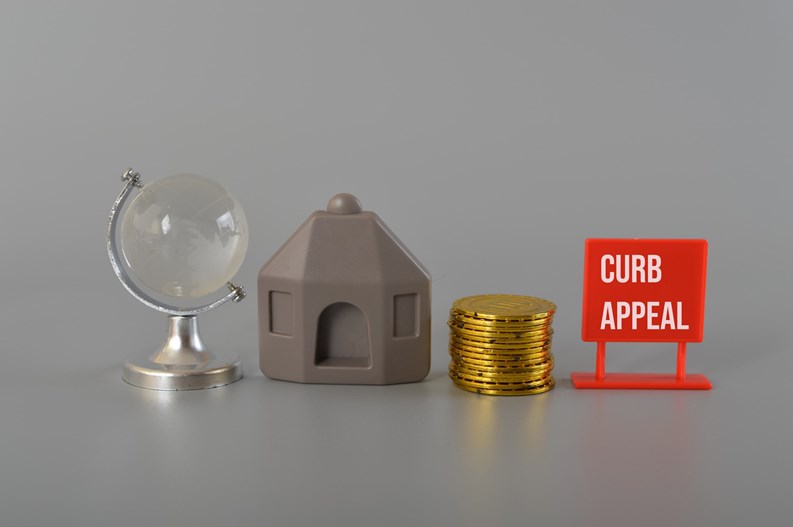 House model, coins, earth globe written with CURB APPEAL.Curb appeal refers to the visual attractiveness of a property, particularly its exterior or front-facing facade, as viewed from the street or sidewalk