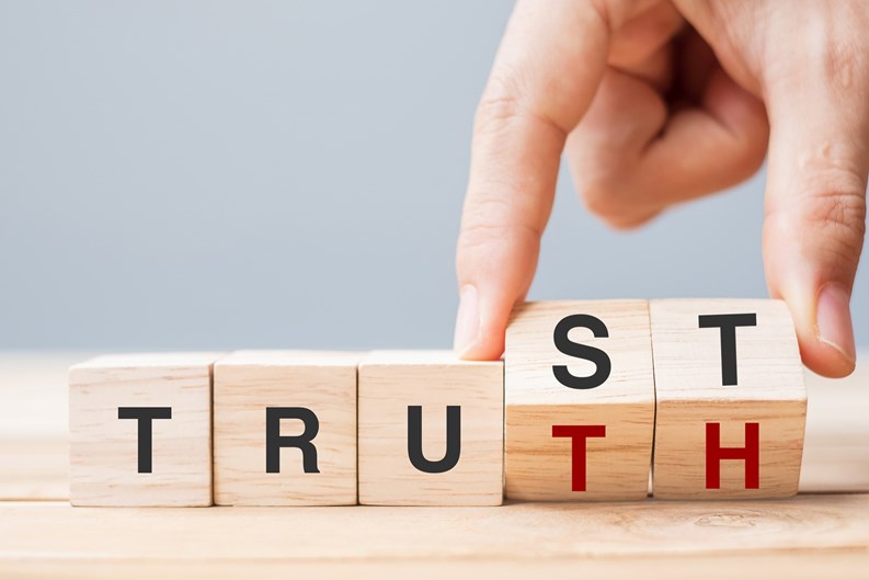 Business man hand change wooden cube block with TRUST and TRUTH business word on table background. Trustworthy, faith, beliefs and honesty concept