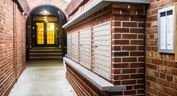 Mailbox & Package Room Design Brick apartment building entrance in downtown NYC New York City with mailbox post mail boxes, empty corridor in evening night with nobody, secured area