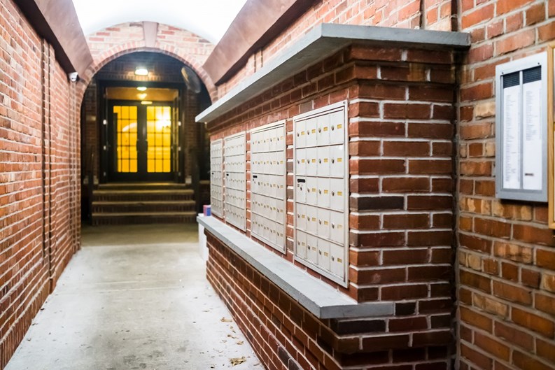 Brick apartment building entrance in downtown NYC New York City with mailbox post mail boxes, empty corridor in evening night with nobody, secured area