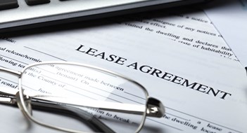 Commercial Leases in Co-ops & Condos Lease Agreement Documents with Glasses, Pen and Calculator