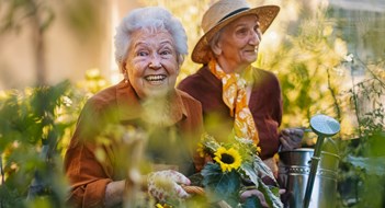 Managing Aging Residents Adapting to Changing Needs Portrait of senior friends taking care of vegetable plants in urban garden in the city. Pensioners spending time together gardening in community garden in their apartment complex. Nursing home residents gardening outdoors. Senior sisters have same hobby.