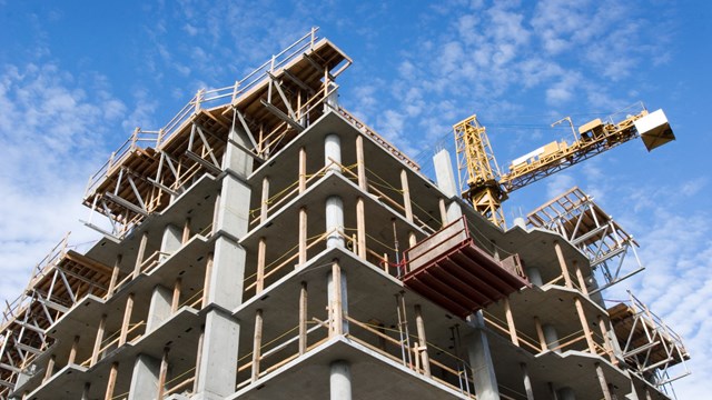 Reinforced steel & concrete building under construction.  Safety guard rails, flyforms and tower crane