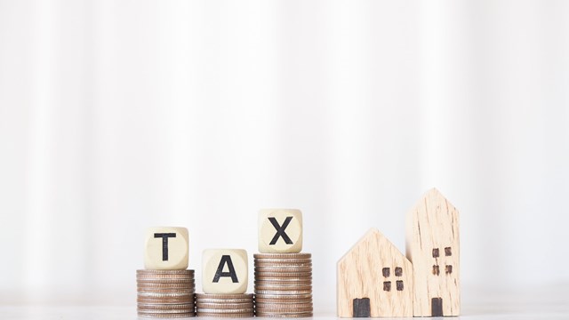 Miniature house, Wooden blocks with the word TAX on stack of coins. The concept of payment tax for house, Property investment, House mortgage, Real estate.