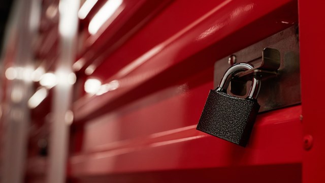 Padlock on closed red metal door in warehouse