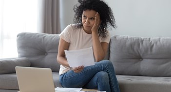 Q&A: Can Treasurer Change Maintenance Increases? African woman sit on couch near pc received utility bills feels concerned about price increase or high taxes, female holds letter from bank about money debt overspend or credit loan rejection concept
