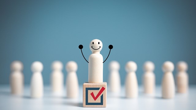 Raise hand wooden figure stands above a wooden cube with vote symbol among another. open-mindedness or public hearing, Elections concept. Volunteers, parties, candidates, constituency electorates.