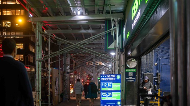 New York, NY, USA, 12-05-2023 New York City night time street scene with scaffolding parking garage entrance and pedestrians. Editorial use only.