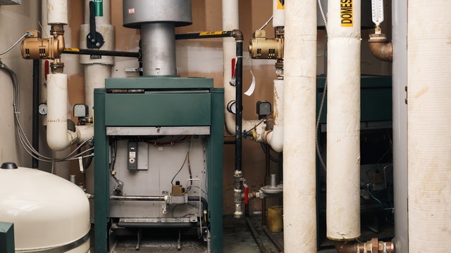 Natural gas heater, hot water tank and hot and cold water pipes. Gas safe, gas technician or plumbing background. Selective focus.
