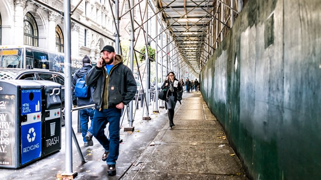 New York City, USA People walking under cover scaffold construction in NYC Manhattan